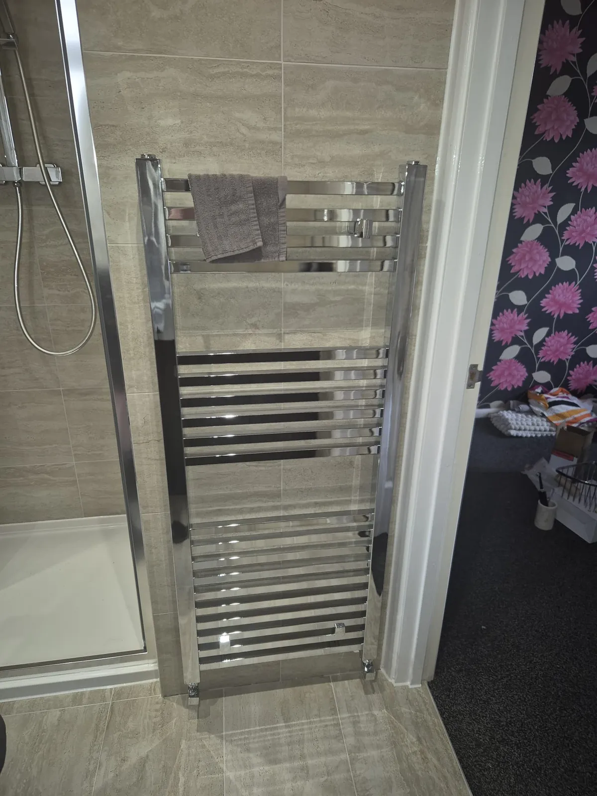 Chrome heated towel rail fitted beside a shower enclosure in a bathroom by GJS in Essex