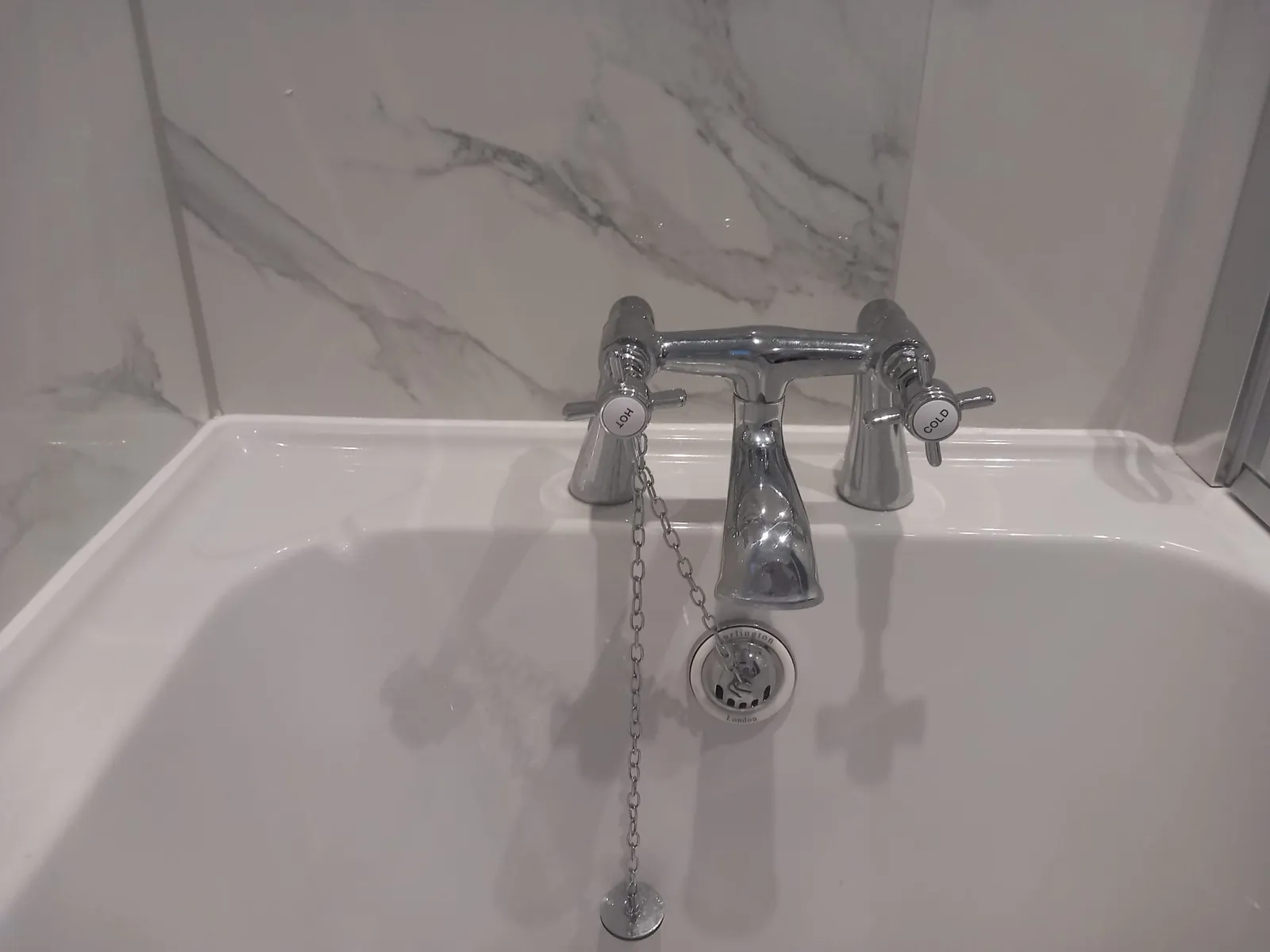 Chrome bath mixer tap with traditional handles on a white bath, fitted by GJS in Essex
