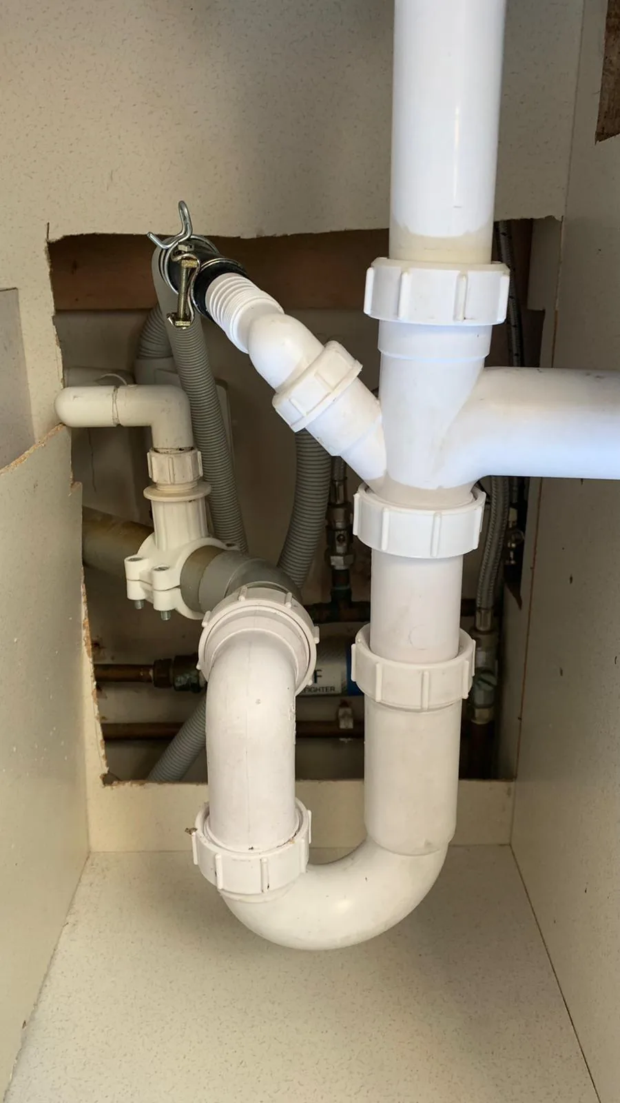 New white waste pipework fitted neatly under a kitchen sink